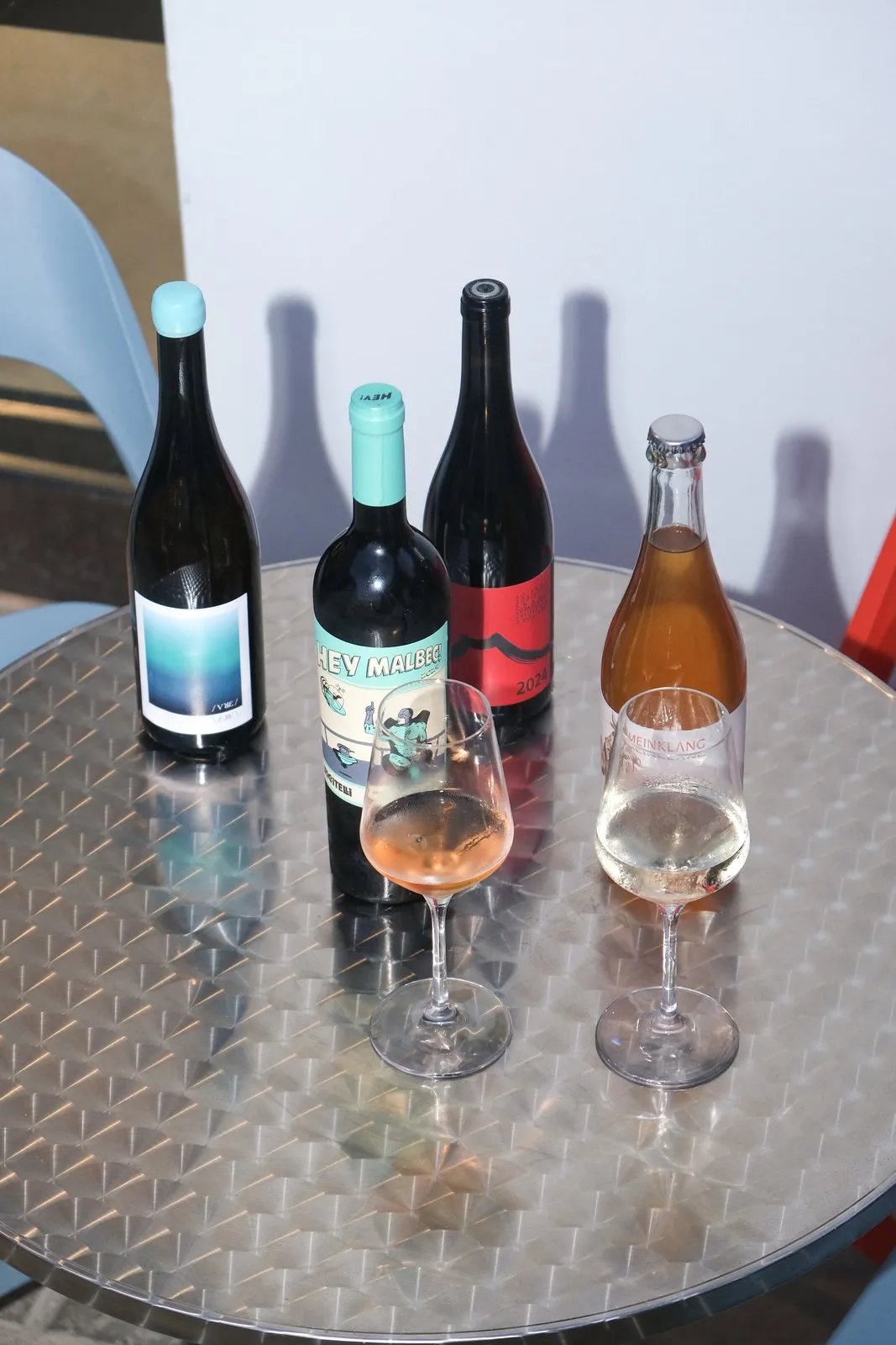 Open bottles of natural wine and two poured glasses on a table at Filomena